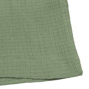 Detail of sage green smocked fabric with textured seersucker finish and precision stitching
