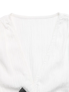 Detailed close-up of white V-neck top showing breathable pleated texture and clean seams
