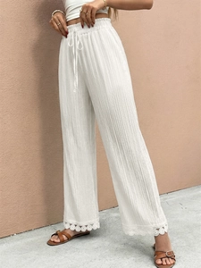 Dettaglio della vita alta elastica con coulisse e bordo in pizzo sui pantaloni bianchi larghi