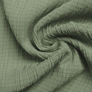Close-up of sage green waffle fabric texture with smocked elastic detail and soft drape