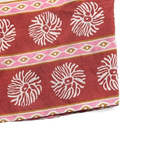 Détail de l'imprimé floral ethnique et de la bordure géométrique sur tissu rouge brique