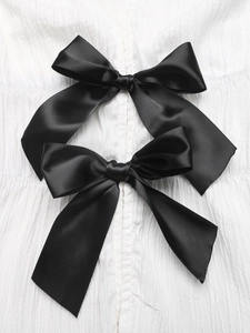 Detail of elegant black satin bows on white pleated fabric with subtle silk luster