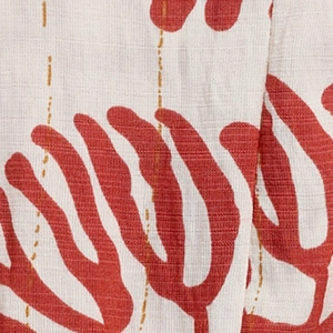 Vue macro du tissu de robe d'été crème avec imprimé corail rouille et coutures dorées