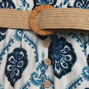 Detail of bohemian floral print fabric with straw belt and wooden buttons on a summer dress