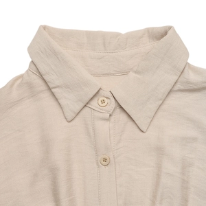 Détail de robe chemise beige montrant le col pointu et les boutons en résine