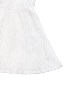 Detailed view of elastic smocked waist and vertical textured white fabric on shirt