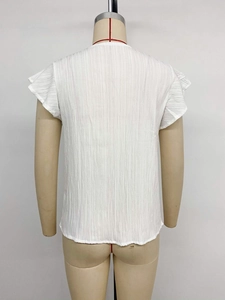 Detail view of white v-neck shirt featuring vertical pleated texture and ruffle cap sleeves