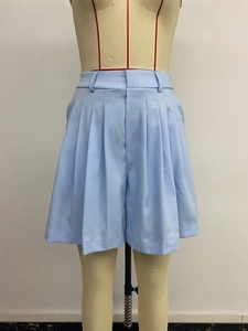 Dettaglio dei pantaloncini da completo a vita alta plissettati celeste con gamba ampia