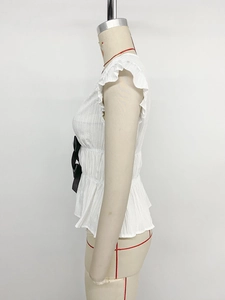 Detail view of white sleeveless peplum top with ruffle shoulders and a black satin bow