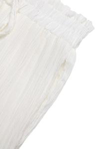 Dettaglio dei pantaloni estivi bianchi con trama stropicciata ed elastico in vita arricciato