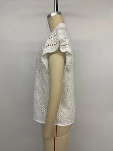 Detail of white summer blouse with hollow embroidery and ruffled cuffs on mannequin