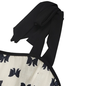 Détail de la bandoulière réglable en ruban noir sur robe crème imprimée de nœuds