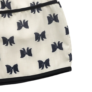 Gros plan sur tissu en toile crème avec imprimé nœuds noirs et passepoil contrasté noir
