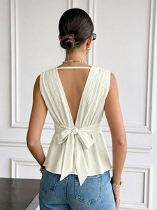 Détail du haut sans manches dos nu avec col en V, texture froissée et nœud élégant en crème