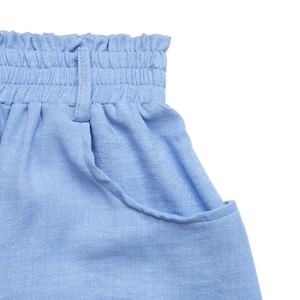 Detail of paperbag waist design with elastic gathers and side pockets on light blue skirt