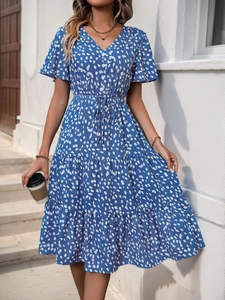 Detail of royal blue V-neck dress with white polka dots, waist tie, and tiered skirt