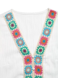 Detail of V-neck crochet floral pattern on white pleated fabric with button accents