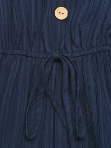 Dettaglio del tessuto plissettato blu navy con bottone in legno e coulisse elastica