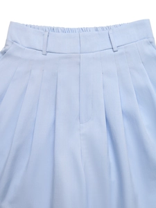 Dettaglio degli shorts a pieghe azzurri con passanti per cintura e vita semielastica