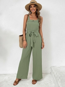 Detail of green sleeveless jumpsuit featuring textured fabric and waist tie design