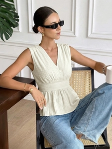 Détail de la blouse sans manches à col en V crème avec taille cintrée et ourlet à basque