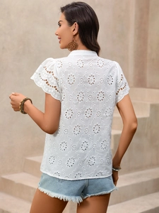 Close-up of white eyelet embroidered shirt with scalloped sleeves and floral textures