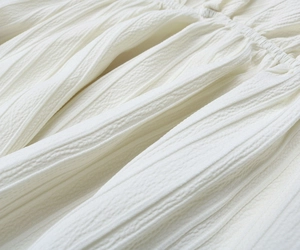 Gros plan détaillé du tissu blanc du chemisier à col en V avec texture plissée