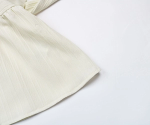 Gros plan sur le tissu plissé ivoire montrant la texture à rayures verticales et les coutures