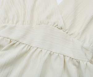 Gros plan du chemisier d'été blanc cassé avec col en V et texture de tissu gaufré
