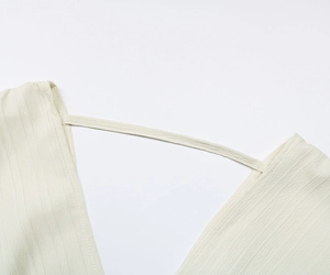 Détail de la blouse crème à col en V montrant le tissu côtelé et la sangle délicate ajustée