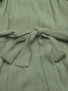 Detailed macro view of the sage green tied waist knot and seersucker fabric texture