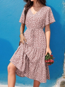 Detail of grey-pink V-neck floral dress with polka dots, ruffled hem and waist tie belt