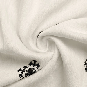 Detailed macro view of white cotton-linen fabric with black floral embroidery patterns