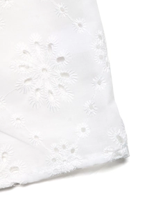 Close-up of white summer shirt featuring floral embroidery and eyelet hollow details