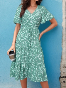 Detail of green floral midi dress with V-neck, white polka dots and tiered ruffle skirt