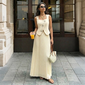 Detailed close-up of sleeveless vest and pleated maxi skirt in beige urban fashion style
