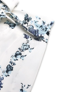 Détail de l'imprimé floral bleu sur tissu blanc avec couture nette et lien de taille