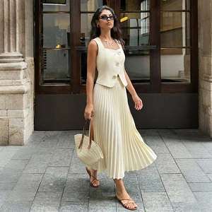 Detail shot of the beige sleeveless vest with large buttons and pleated midi skirt