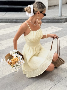 Detail of yellow camisole dress featuring textured jacquard fabric and tiered ruffles