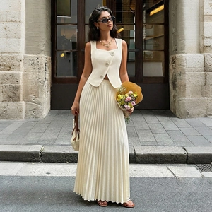 Detail view of cream white sleeveless vest with large buttons and pleated skirt set