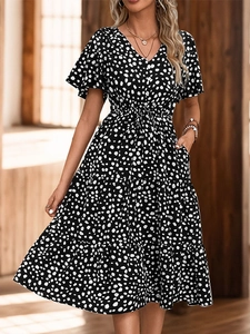Detailed view of black and white polka dot V-neck midi dress with tiered skirt and pockets