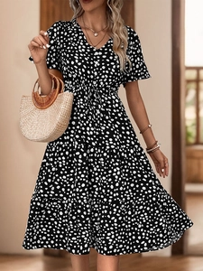 Detail of V-neck neckline with button closure and black and white spotted print pattern