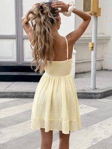Detail of the yellow sun dress back featuring smocked elastic waist and ruffled hemline