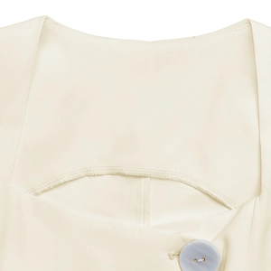 Detail of a cream-white sleeveless top featuring layered neckline and a purple pearl button