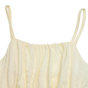 Detail of light yellow smocked dress featuring textured plaid pleated fabric and thin straps