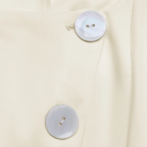 Detail of twill fabric texture and pearlescent buttons on a cream sleeveless top