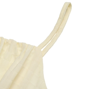 Detailed view of cream camisole dress strap connection and textured plaid fabric weave