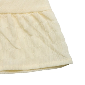 Detail of the pleated hem on a pale yellow summer dress showing fine stitching and fabric texture