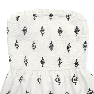 Detail of smocking elastic waist with black geometric diamond embroidery on white fabric