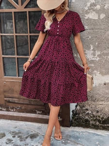 Detail view of the V-neckline and decorative front buttons on the wine red polka dot dress